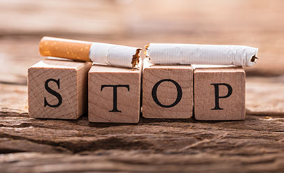 Broken cigarette sitting on top of wooden blocks that spell out stop